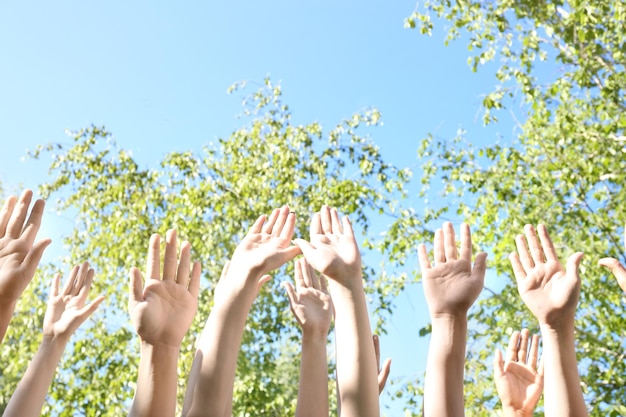 Young people putting hands in air together outdoors Volunteering concept