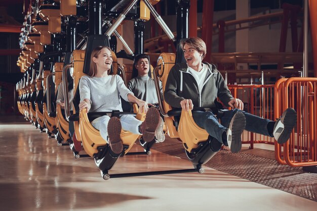 Young people raise their feet while sitting on the carousel