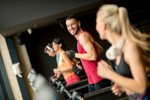 Young people running on treadmills in modern gym