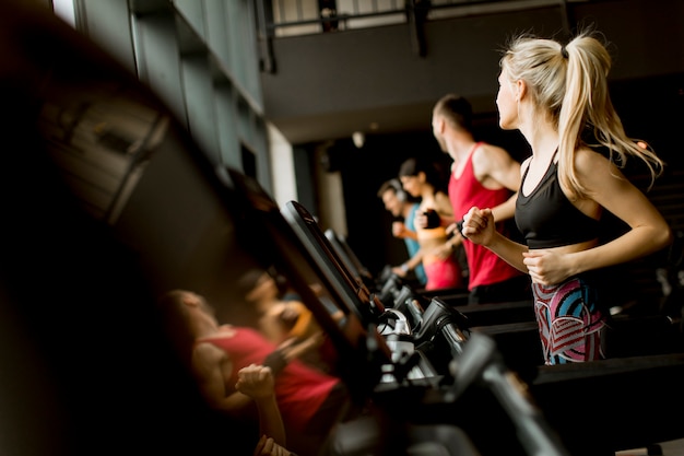 Young people running on treadmills in modern gym