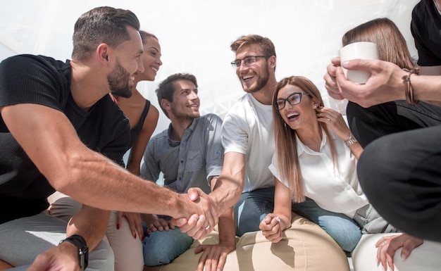 Young people shaking hands in a circle of friends