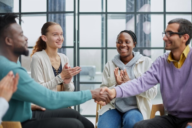 Young people shaking hands in a circle of likeminded people