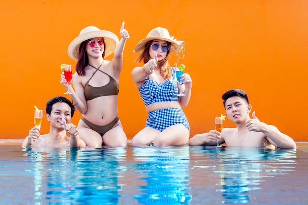 Young people showing thumbs up on poolside