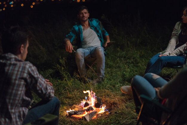 The young people sit near the bonfire. evening night time