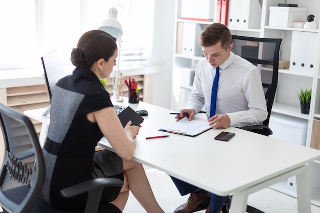 I giovani si siedono in ufficio al tavolo del computer e lavorano con i documenti.