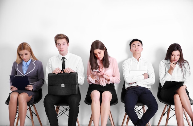 Young people sitting on a chairs in white hall