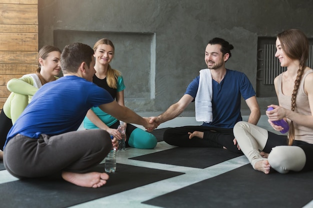 Giovani seduti in cerchio prima dell'allenamento. uomini che si stringono la mano. insieme e sostegno, moda sportiva giovanile e tempo libero attivo. punto di vista, copia spazio