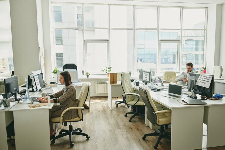 Photo young people sitting in half-empty office during coronavirus period and using modern devices
