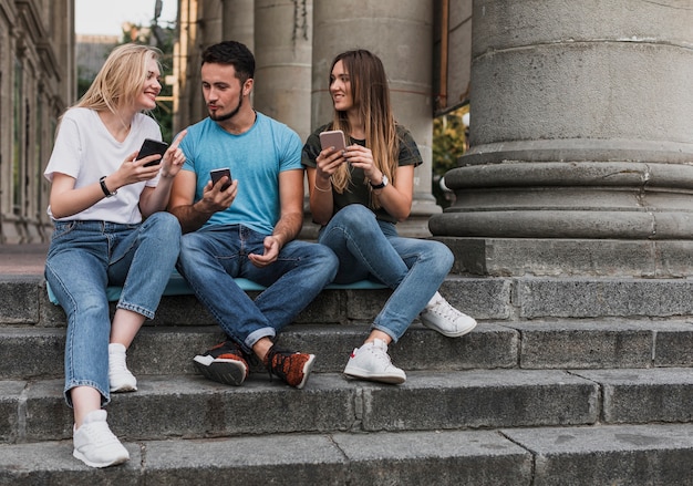 Young people sitting on stairs and checking their phones
