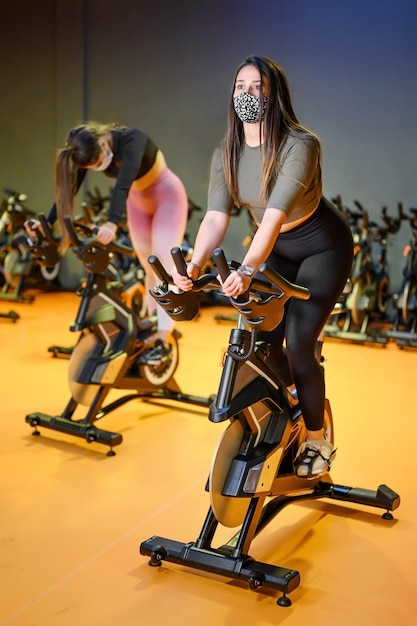 Young People Spinning in the fitness gym with protective face mask during coronavirus outbreak.