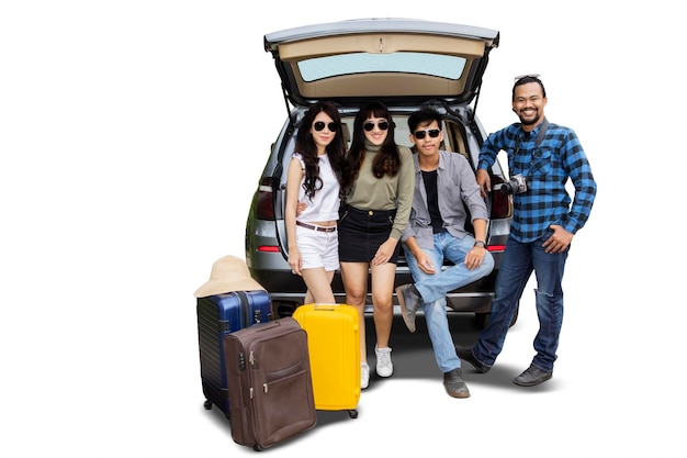 Young people standing behind the car with suitcase