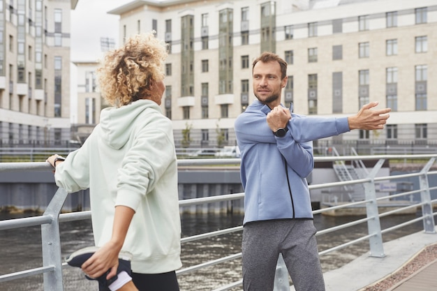 Young people standing on the street and warming up before sports training in the city