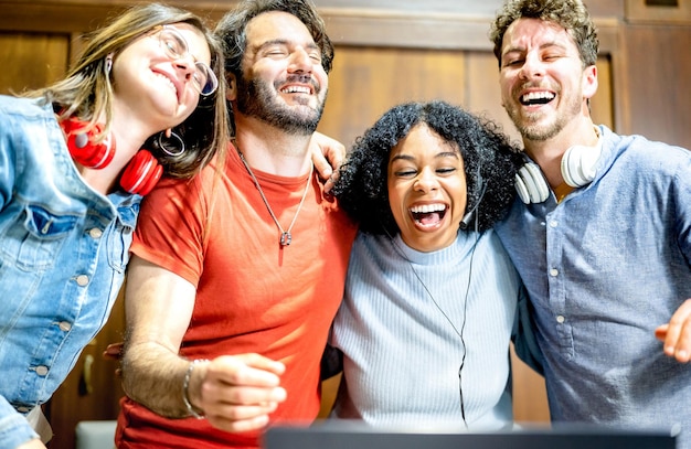 Young people students having fun laughing together with laptop at startup studio