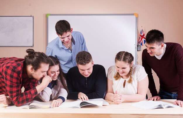 Young people studying with books on white desk Beautiful girls and guys working together wearing casual clothes