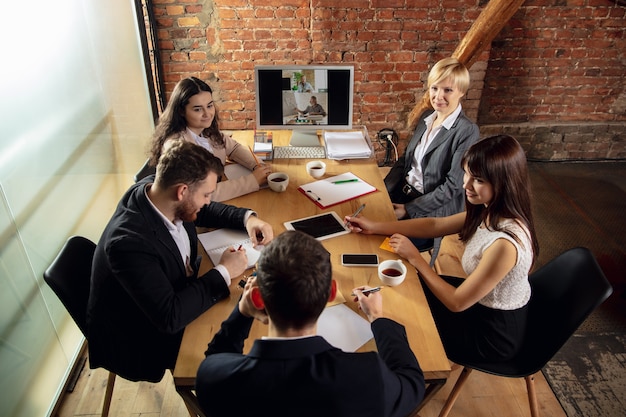 Young people talking, working during videoconference with colleagues at office or living room