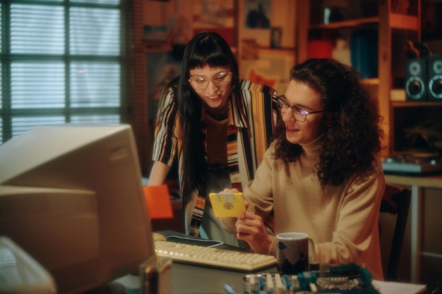 Young people using floppy disk to save information from computer during their teamwork in garage