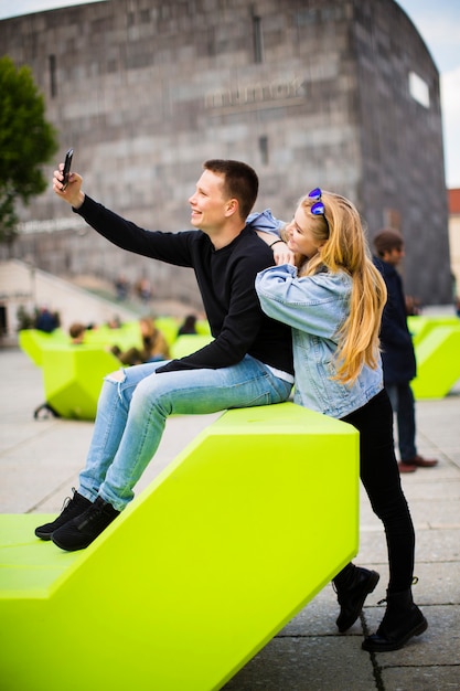 Young people using mobile phone on the modern bench on street in Vienna, Austria