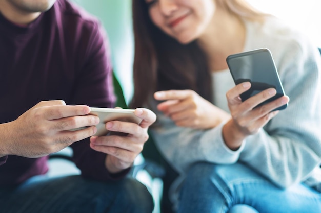 Young people using and plying games on mobile phone while sitting together