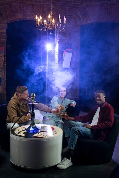 Young people vaping from a hookah in a bar