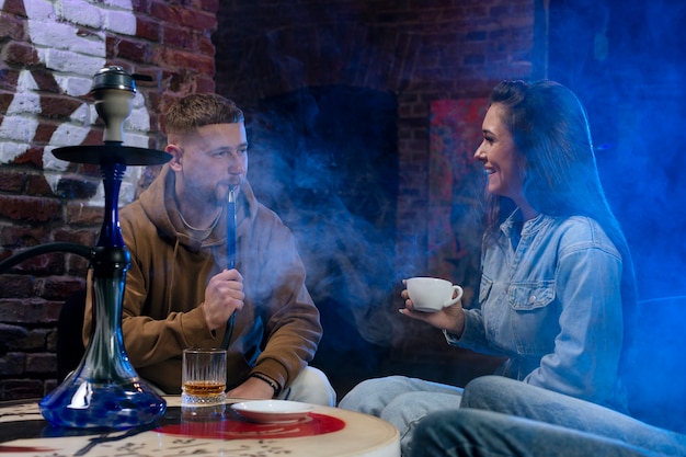 Foto giovani che svapano da un narghilè in un bar