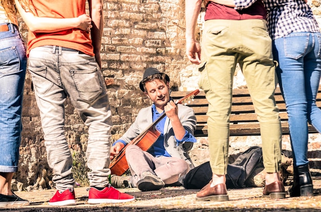 Young people watching street artist performer playing acoustic classic guitar outdoors