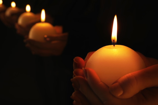 Young people with burning candles in darkness