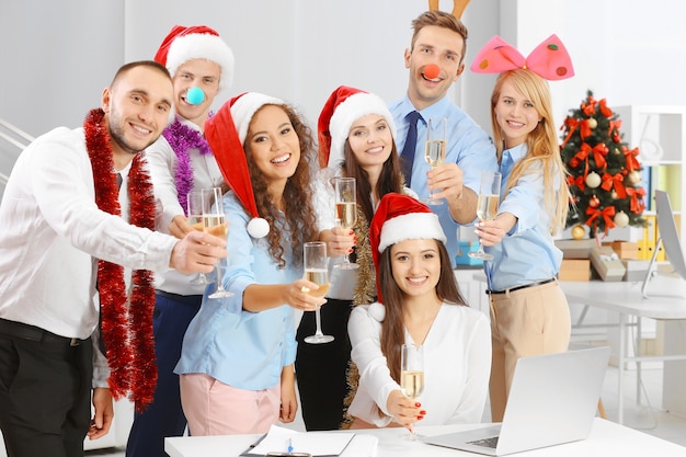 オフィスの企業パーティーでクリスマスを祝うシャンパンのグラスを持つ若者