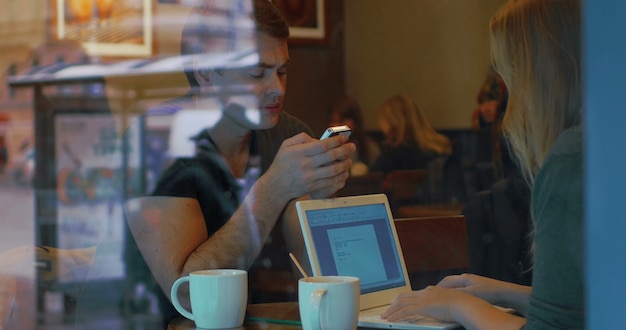 Young people with smart phone and laptop in cafe