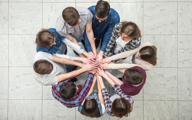 Young people with their hands together in a circle.