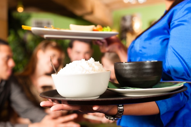 Photo young people with waitress eating in thai restaurant