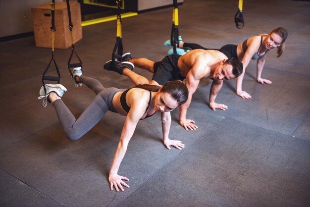 写真 若い人達が trx を使って運動する