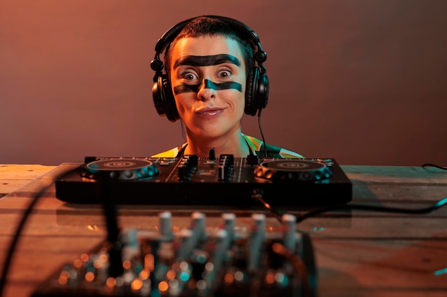 Young performer acting funky looking at mixer, being focused on\
control buttons at dj turntables over background. looking closely\
at audio equipment to mix techno music, stereo instrument.