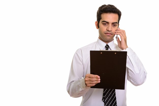 Young Persian businessman talking on mobile phone and reading clipboard