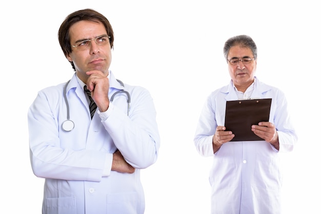 Young Persian man doctor thinking with senior man doctor looking at clipboard