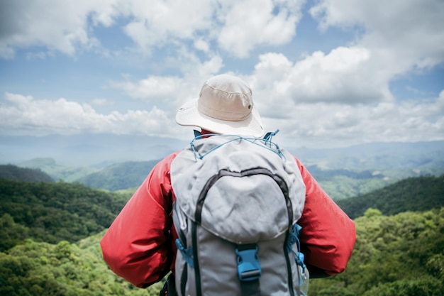 Young person hiking male on top rock Backpack man looking at beautiful mountain valley