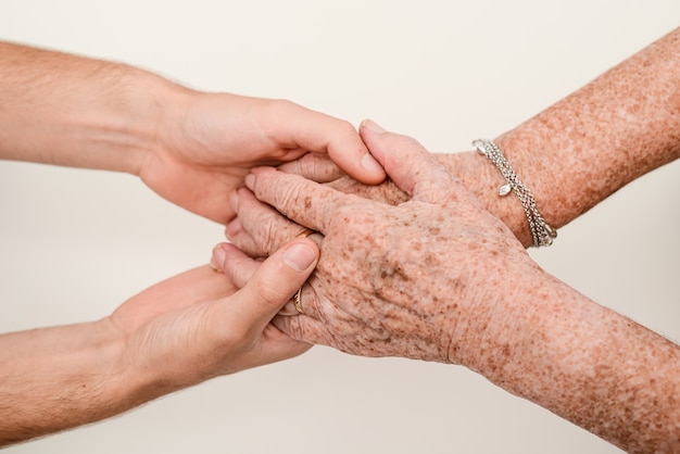 Young person holding senior elderly people hand close up