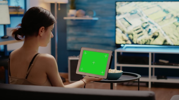 Young person looking at tablet with horizontal green screen