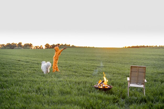 暖炉のそばの緑の野原で犬と遊ぶ若者