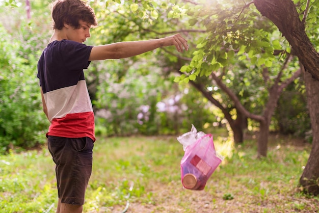 Young person throw the plastic package with trash away in the nature park zone environmental pollution