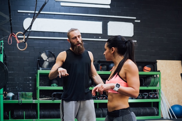 Young personal trainer indoor gym talking with woman athlete