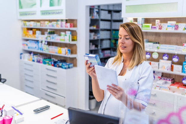  Young pharmacist holding a tablet and box of medications.