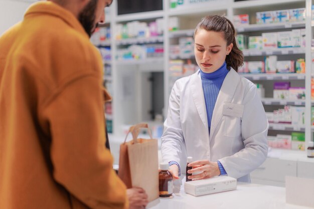 Photo young pharmacist selling medications to the customer