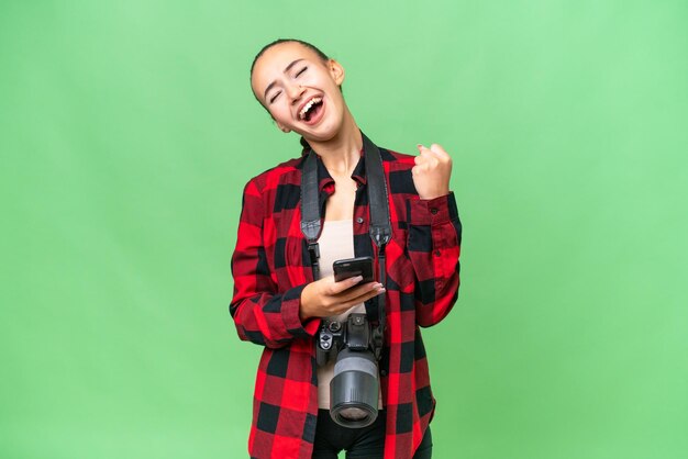 Young photographer Arab woman over isolated background with phone in victory position