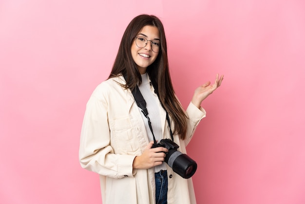핑크색에 고립 된 젊은 사진 작가 브라질 소녀는 올 초대를 위해 손을 옆으로 확장