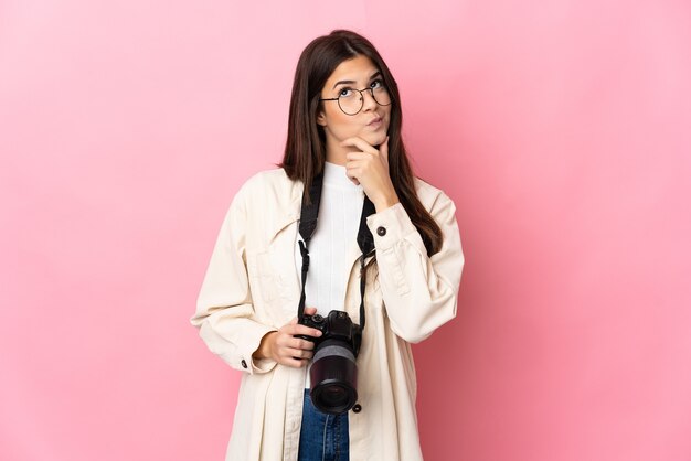 疑いを持ってピンクに分離された若い写真家ブラジル人女性