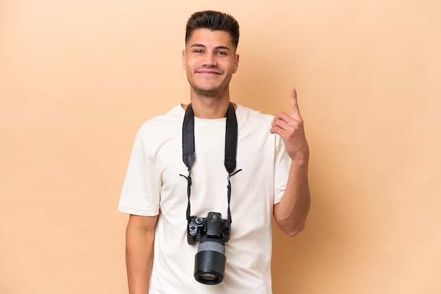 Young photographer caucasian man isolated on beige background pointing with the index finger a great idea