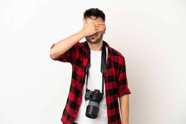 Young photographer caucasian man isolated on white background covering eyes by hands. Do not want to see something