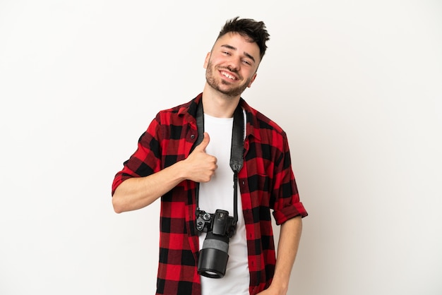 Young photographer caucasian man isolated on white background giving a thumbs up gesture