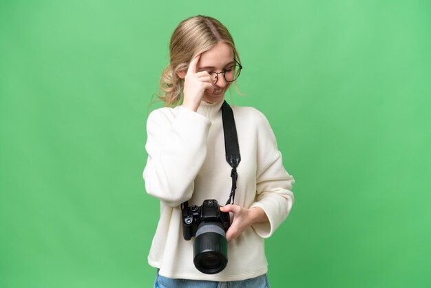 孤立した背景が笑っている若い写真家の英語の女性