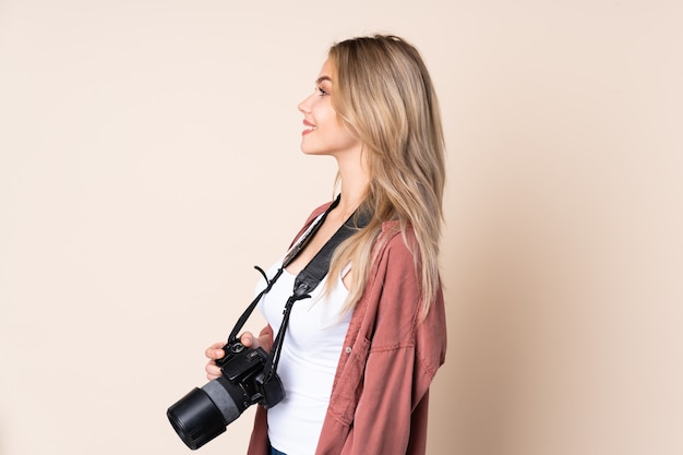 Young photographer girl over wall in lateral position